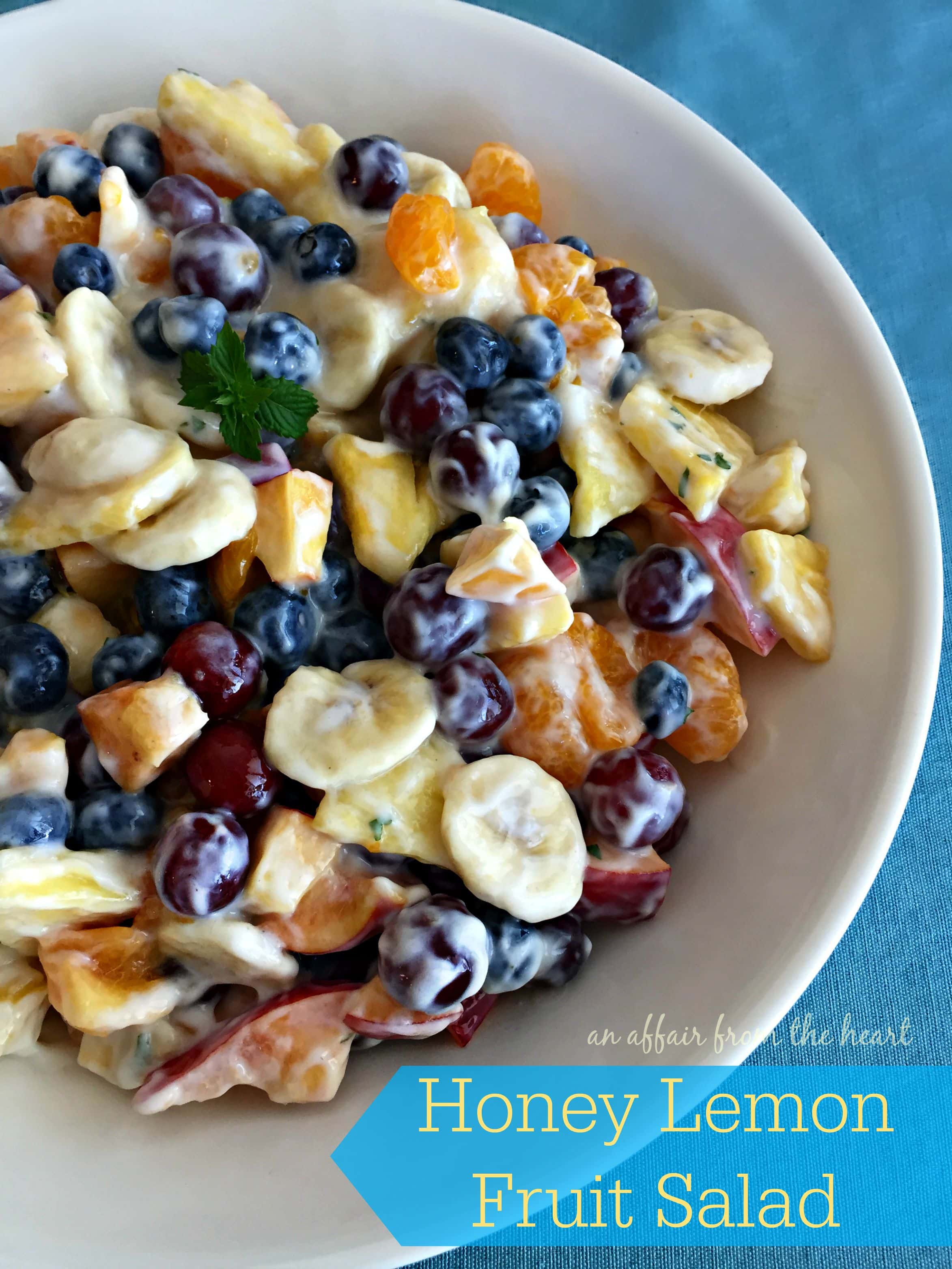 fruit salad in a white bowl with text "Honey Lemon Fruit Salad"