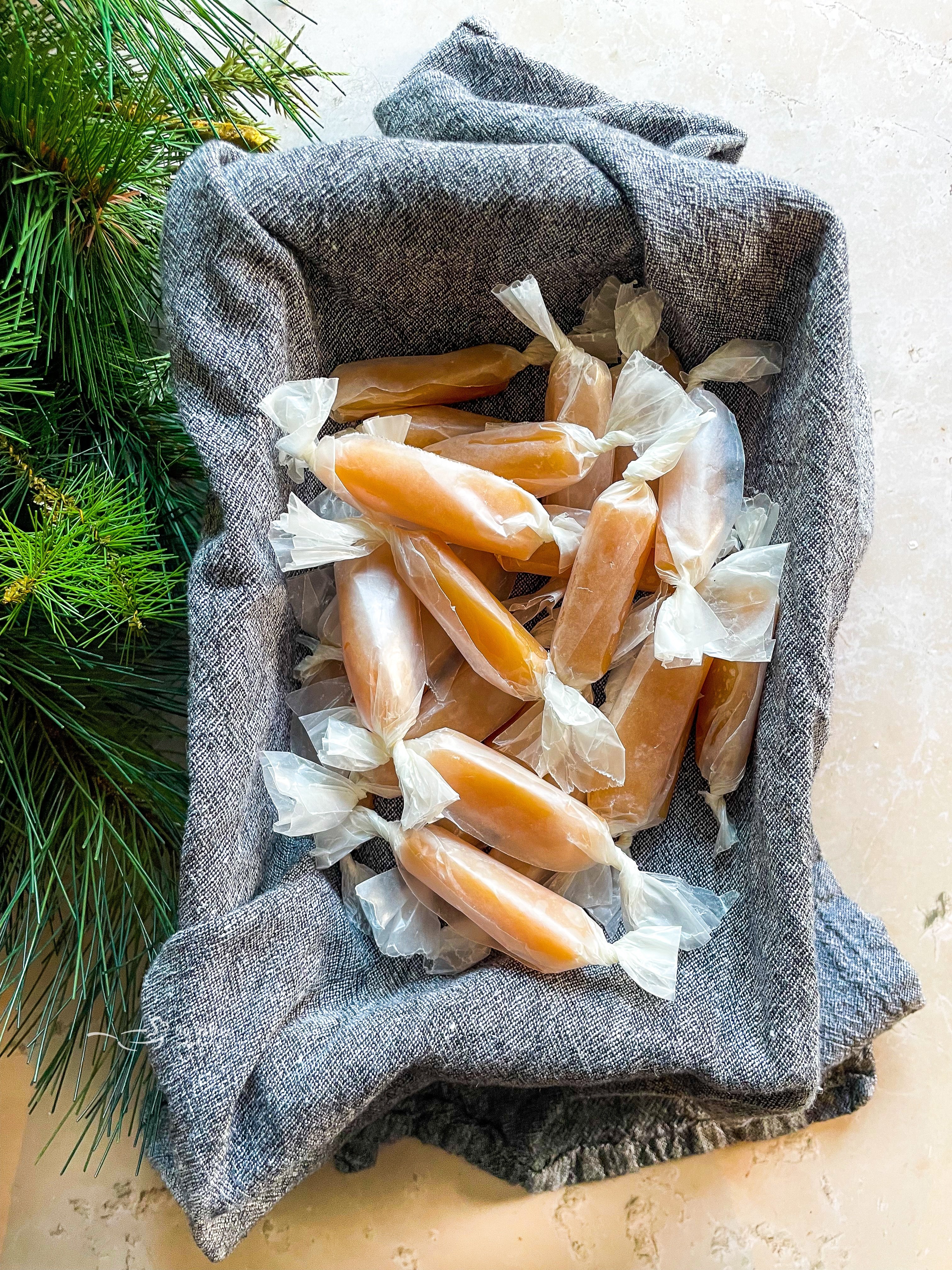 Wrapped homemade caramels in a blue cloth lined dish.